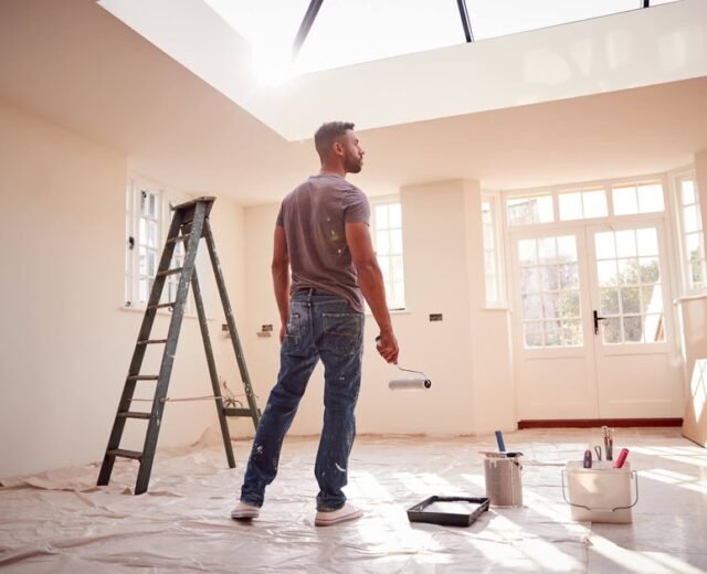 Painter rolling a wall in a bright room